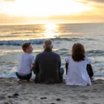 Family sitting together watching the sunset on a UK sandy beach