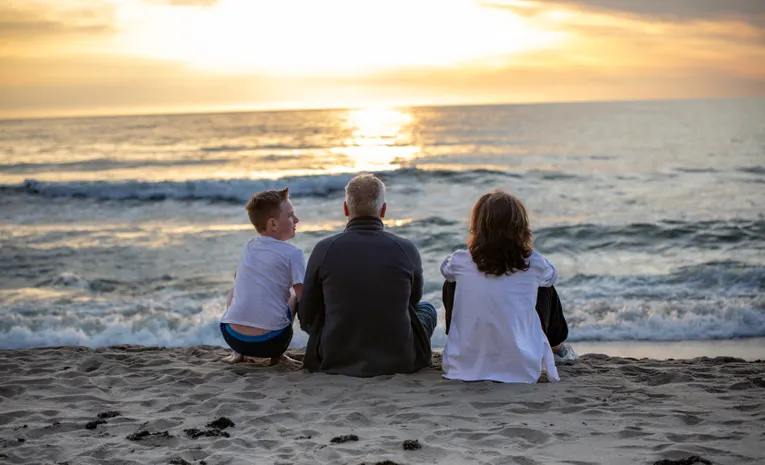 Family sitting together watching the sunset on a UK sandy beach