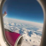 View through an airplane window showing sky and clouds during flight