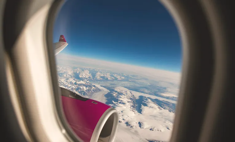 View through an airplane window showing sky and clouds during flight
