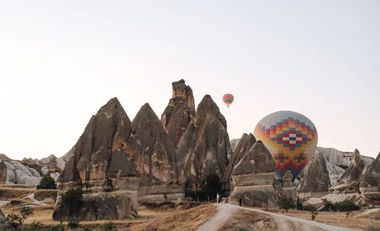 Colourful hot air balloons floating over Cappadocia's rock formations at sunrise